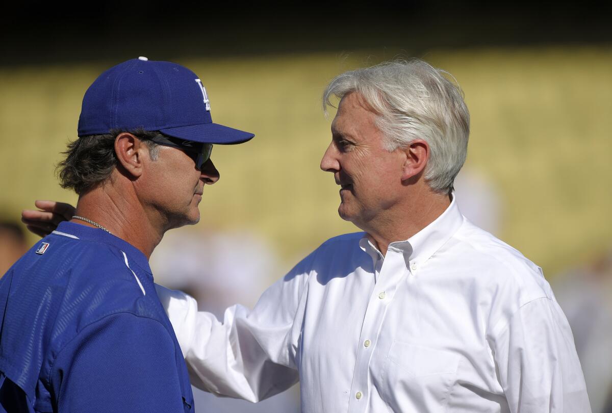 Dodgers Manager Don Mattingly talks with team co-owner Mark Walter, right, before a game against the Cincinnati Reds on Aug. 14.