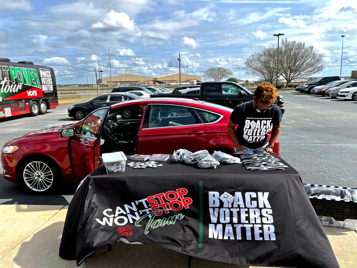A woman sets up merchandise at a booth labeled "Black Voters Matter."