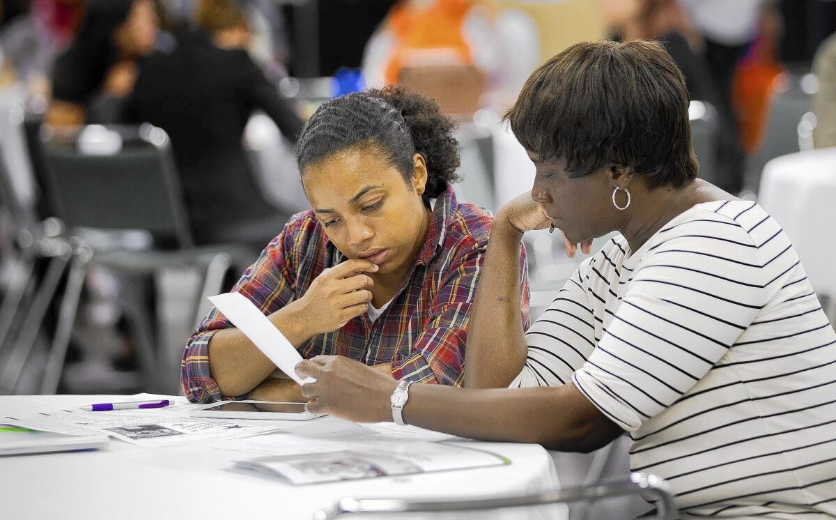 Ebony Reyes, 25, left, of Anaheim helps her mom, Evon Rezk, 50, fill out a job application at a job fair in Anaheim in June. Unemployment rates rose by a tenth of a percentage point in July to 6.2%.