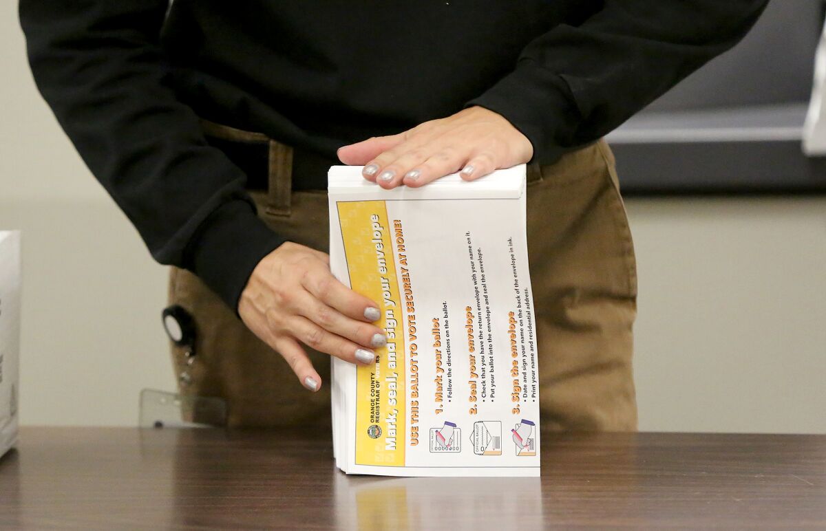 Workers stack and sort ballot packets at the Orange County Registrar of Voters facility in Santa Ana on Wednesday.