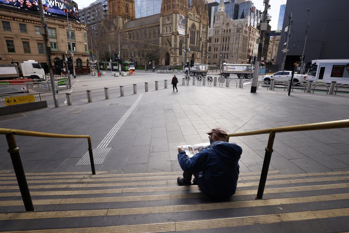A man reads a newspaper on the steps of Flinders Street Station in Melbourne, Australia, Wednesday, Aug. 11, 2021. Australia's second-largest city has extended its lockdown in a bid to eliminate COVID-19 while authorities in Sydney flagged restrictions easing for vaccinated residents despite the delta variant continuing to spread. (AAP Image/Daniel Pockett)