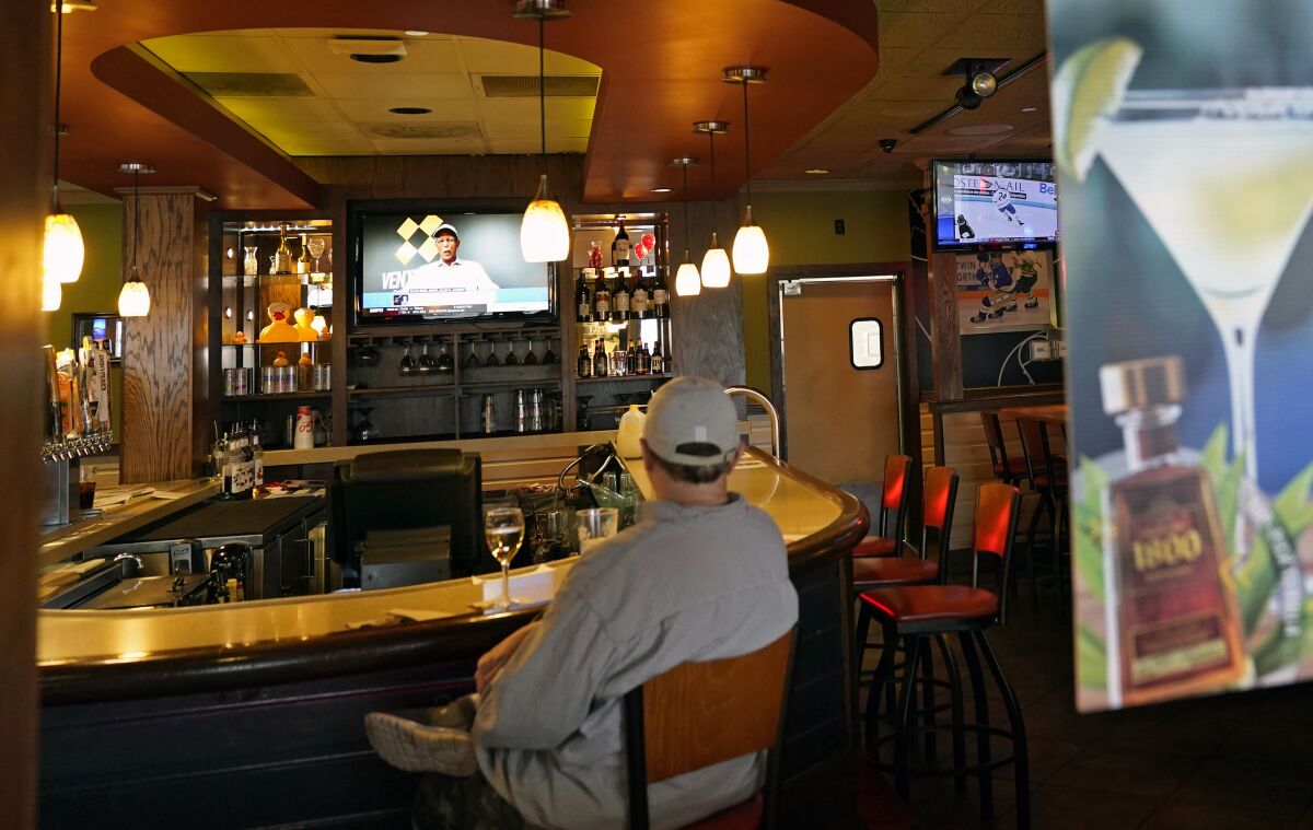 A customer sits at a bar, Tuesday, Nov. 10, 2020, at a Bloomington, Minn., restaurant. Minnesota Gov. Tim Walz announced restrictions that bars and restaurants will be required to end dine-in service between 10 p.m. and 4 a.m., beginning Friday in an effort to slow the spread of the COVID-19 virus. (AP Photo/Jim Mone)