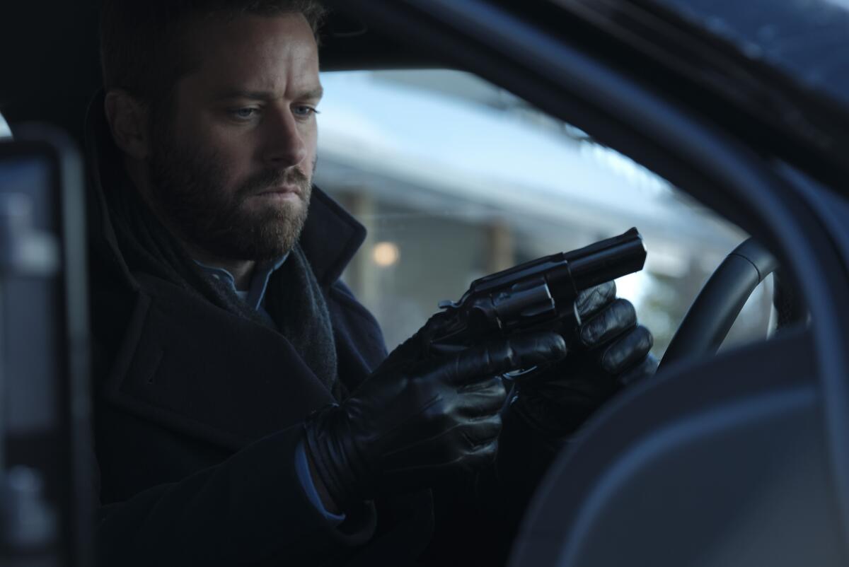 Armie Hammer holds a gun