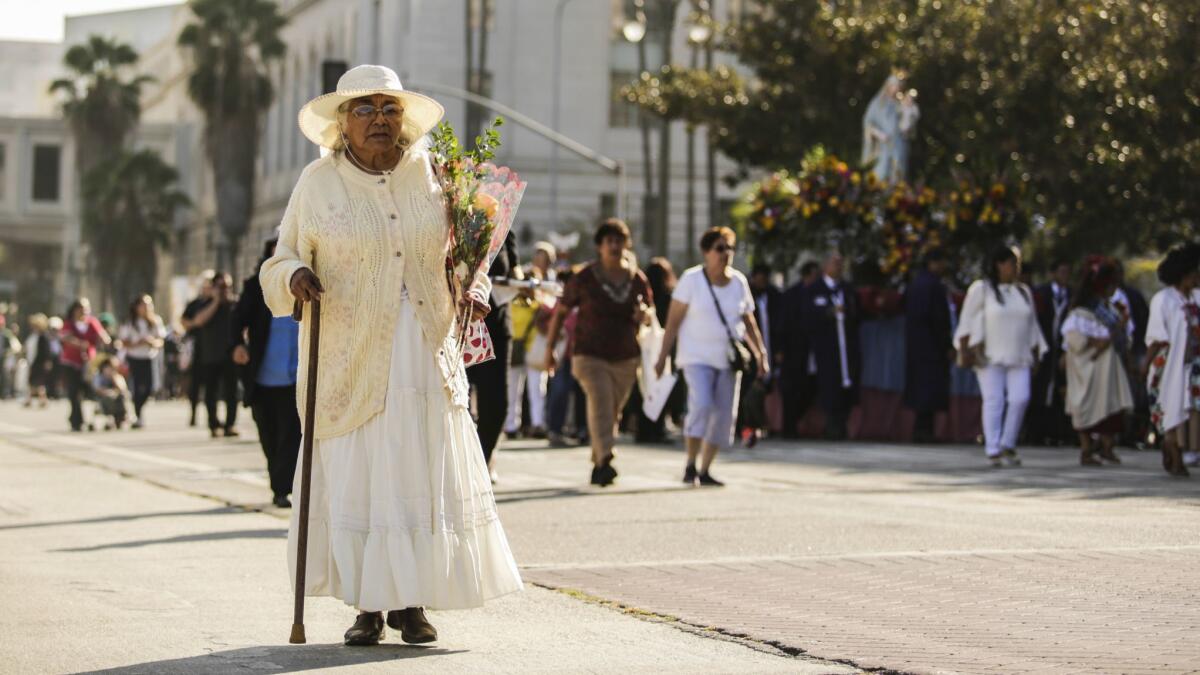 Catarina Atilano prays with her rosary as she walks through downtown Los Angeles.