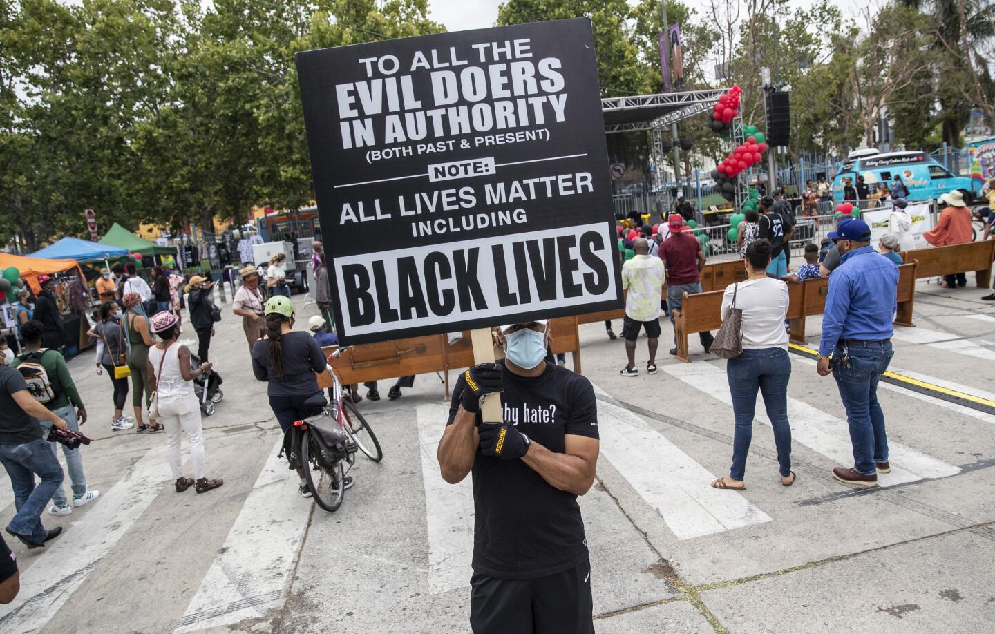 A man holds a sign reading "All lives matter including Black lives"