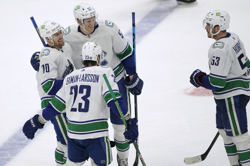 Vancouver Canucks left wing Tanner Pearson, left, is greeted by teammates after he scored an empty-net goal during the third period of the team's NHL hockey game against the Seattle Kraken, Saturday, Jan. 1, 2022, in Seattle. The Canucks won 5-2. (AP Photo/Ted S. Warren)