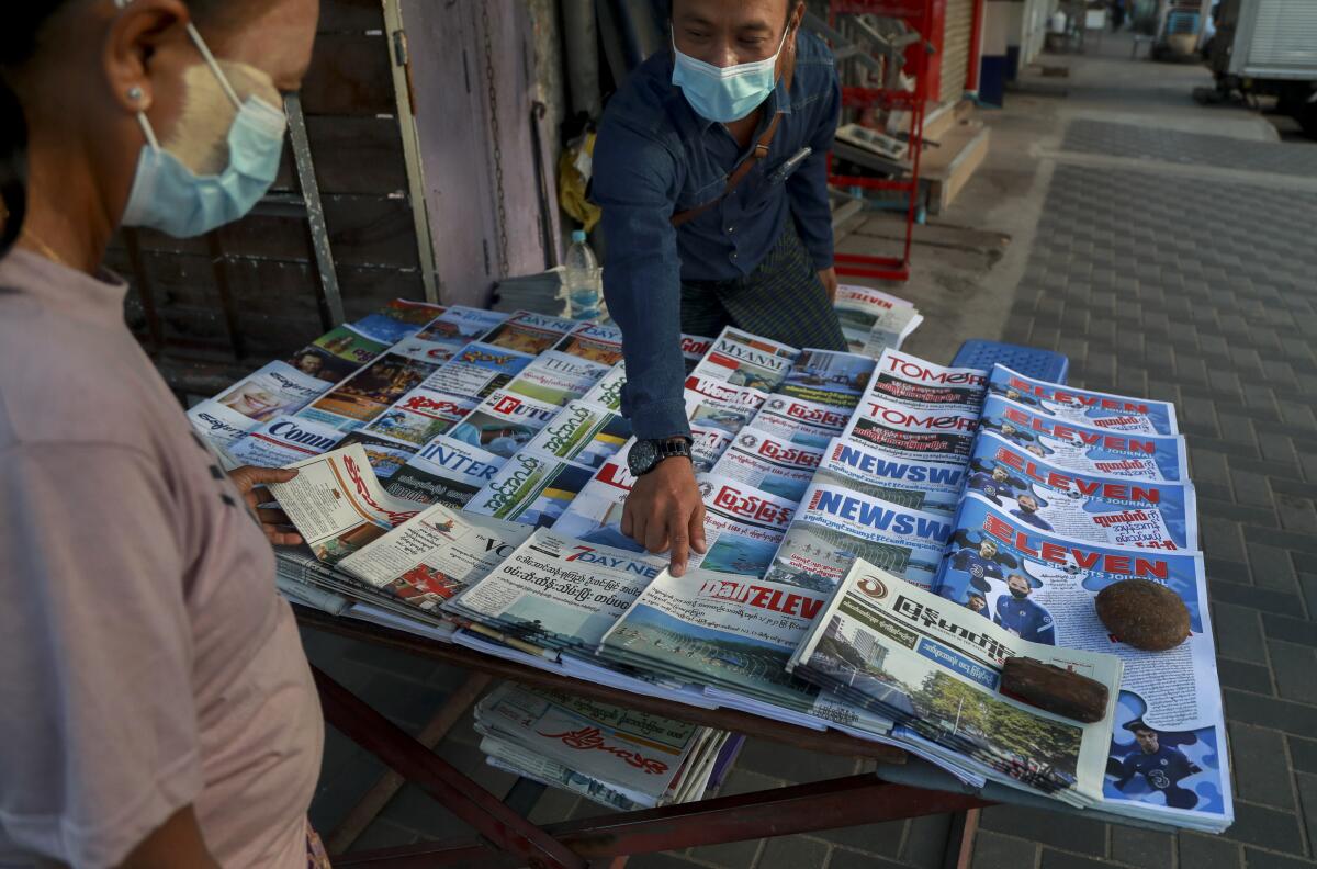 A newspaper seller points at a front page.