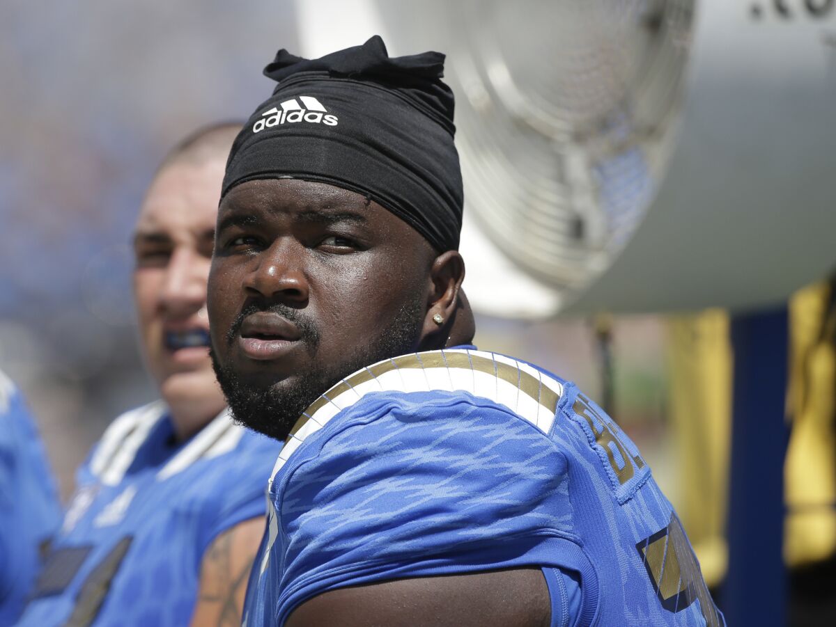 UCLA offensive lineman Caleb Benenoch sits on the bench during the first half of a gane against Virginia at Rose Bowl on Sept. 5.