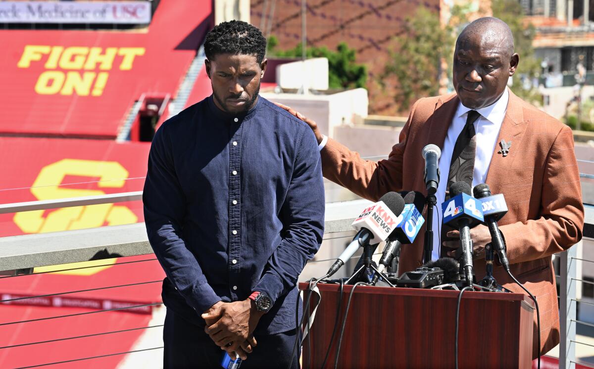 Former USC running back Reggie Bush speaks with his lawyer Ben Crump during a news conference Wednesday at the Coliseum.