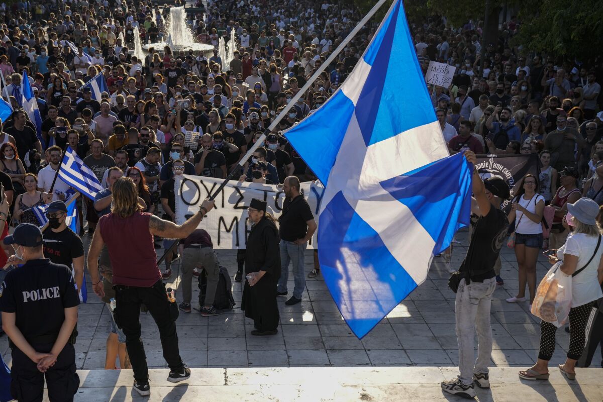 Anti-vaccine protester hold Greek flags during demonstration at Syntagma square, central Athens, on Wednesday, July 14, 2021. Some thousands of anti-vaccine demonstrators gathered in Greece's two largest cities Wednesday over plans to make the vaccine available to children from age 15. Just over 50% of Greeks and country residents have received at least one dose of the COVID-19 vaccine.(AP Photo/Petros Giannakouris)
