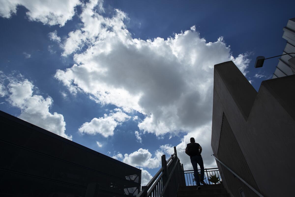 A man makes his way to the second story of a plumbing store in Los Angeles under partially cloudy skies.