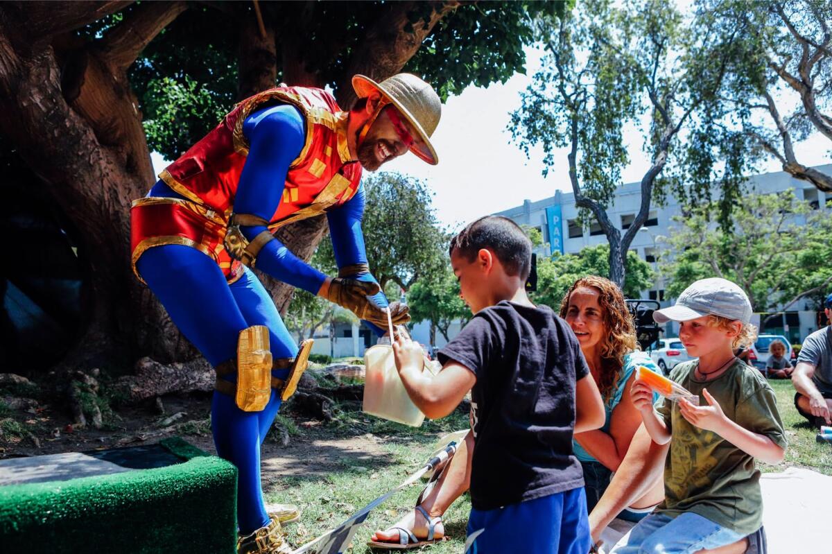 A man dressed as a Power Ranger gives treats to kids.