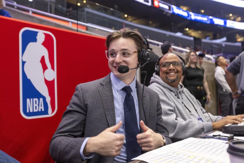Carlo Jimenez, 22, the new radio play-by-play voice of the LA Clippers before a game at the Crypto.com arena in Los Angeles, Calif. He is the only Hispanic radio play-by-play voice on American broadcasts in the NBA. Radio broadcast engineer Jake Warner (right) looks on.