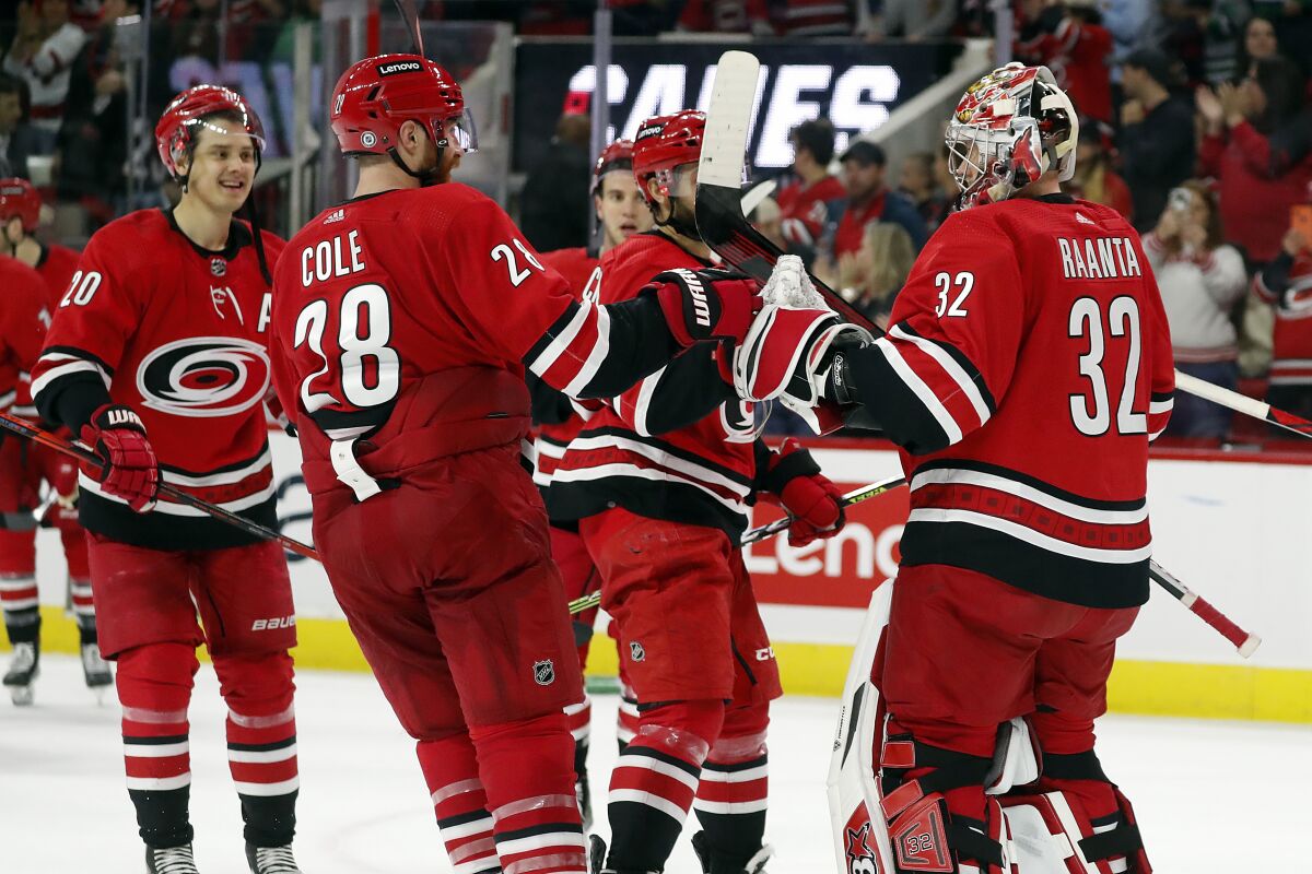 Carolina Hurricanes goaltender Antti Raanta (32) is celebrates with teammates Vincent Trocheck, center, Ian Cole (28) and Sebastian Aho (20) after the team's win over the New Jersey Devils in an NHL hockey game in Raleigh, N.C., Thursday, April 28, 2022. (AP Photo/Karl B DeBlaker)