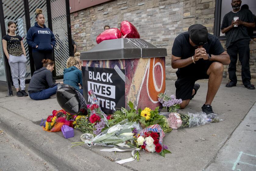 People gather and pray around a makeshift memorial in Minneapolis on Tuesday near the site where a black man, who was taken into police custody the day before, later died.