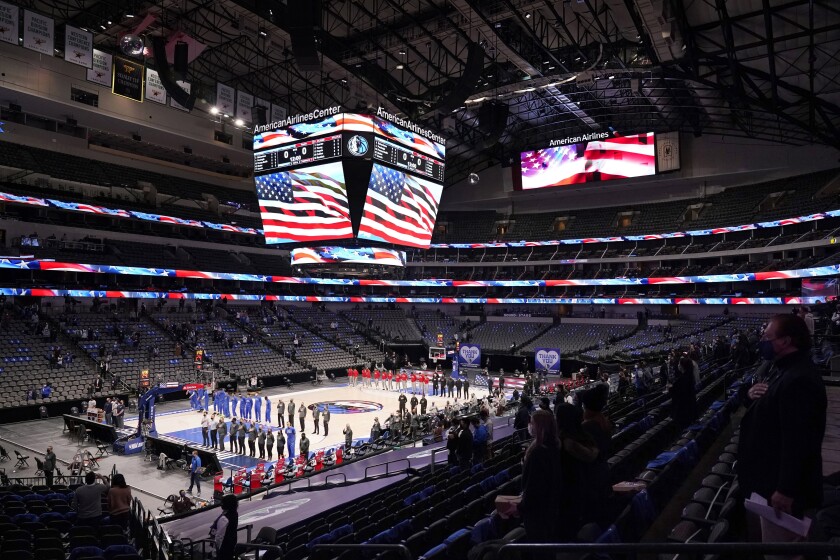 The Dallas Mavericks and Atlanta Hawks, along with a limited fan attendance, stand during the playing of the national anthem before the first half of an NBA basketball game in Dallas, Wednesday, Feb. 10, 2021. (AP Photo/Tony Gutierrez)