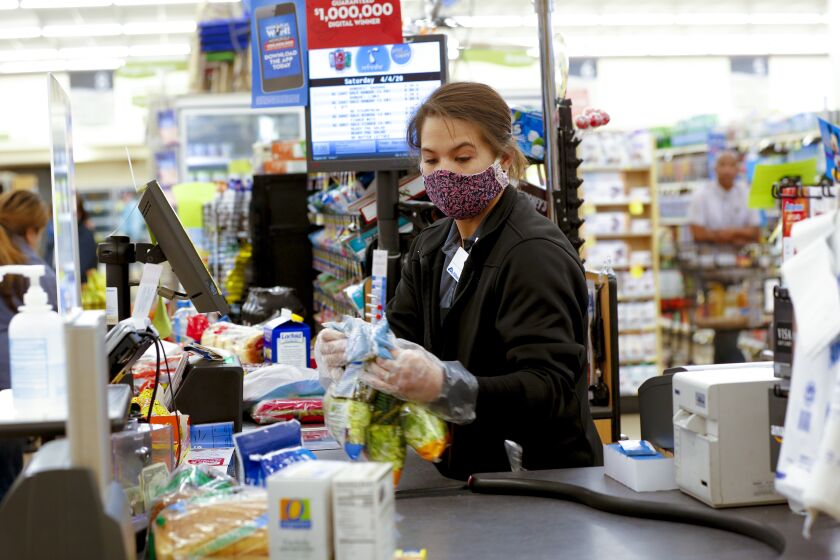 Krista Taylon a cashier at the Albertsons in San Carlos wore the required cloth mask. Effective midnight Friday all employees at grocery stores are required to wear a cloth covering their face. This is an added measure of precaution in addition to the earlier required sneeze guards installed late in March.