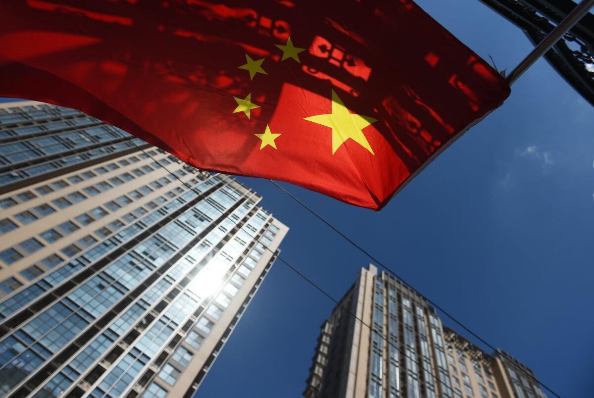 A Chinese flag flies near apartment buildings in Beijing earlier this month. A new report said China's economy is not slowing, as some investors fear.