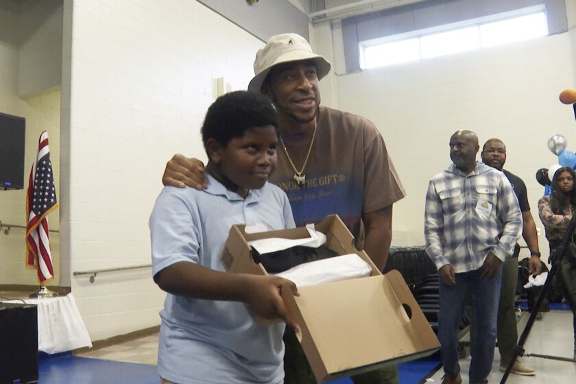 Rapper and actor Ludacris, right, smiles with a student who received new shoes at Miles Intermediate Elementary School in Atlanta on Wednesday, Dec. 7, 2022. (AP Photo/Sharon Johnson)