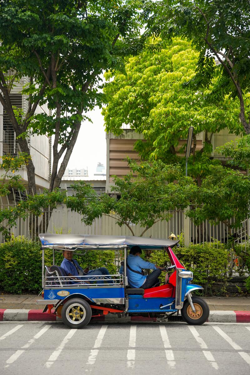 A tuk tuk driver waits on the side of the road outside of Samyan Market in Bangkok.