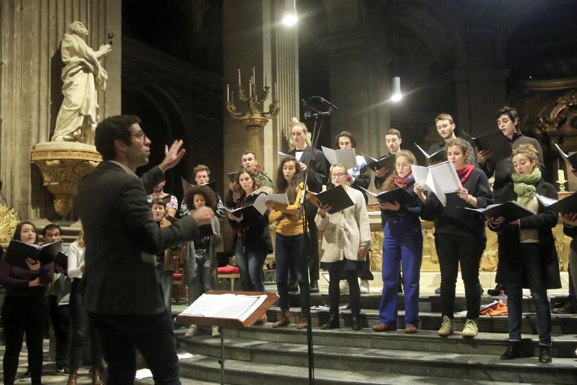 In this photo taken Monday, Dec. 16, 2019, Notre Dame cathedral choir's director Henri Chalet directs the Notre Dame choir during a rehearsal at the Saint Sulpice church in Paris. Notre Dame Cathedral kept holding services during two world wars as a beacon of hope amid bloodshed and fear. It took a fire in peacetime to finally stop Notre Dame from celebrating Christmas Mass for the first time in more than two centuries. (AP Photo/Michel Euler)