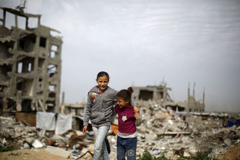 Palestinian children stand next to Gaza City buildings destroyed during last year's conflict between Israel and Hamas-led militants.