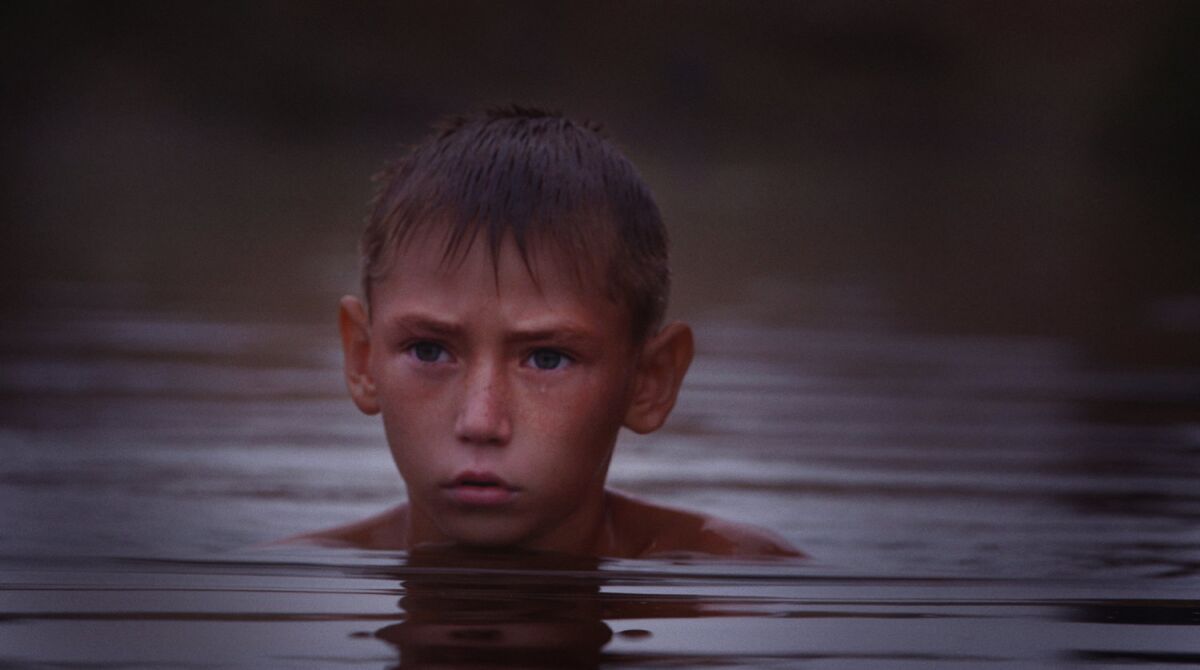 A boy's head sticks up above the surface of a river