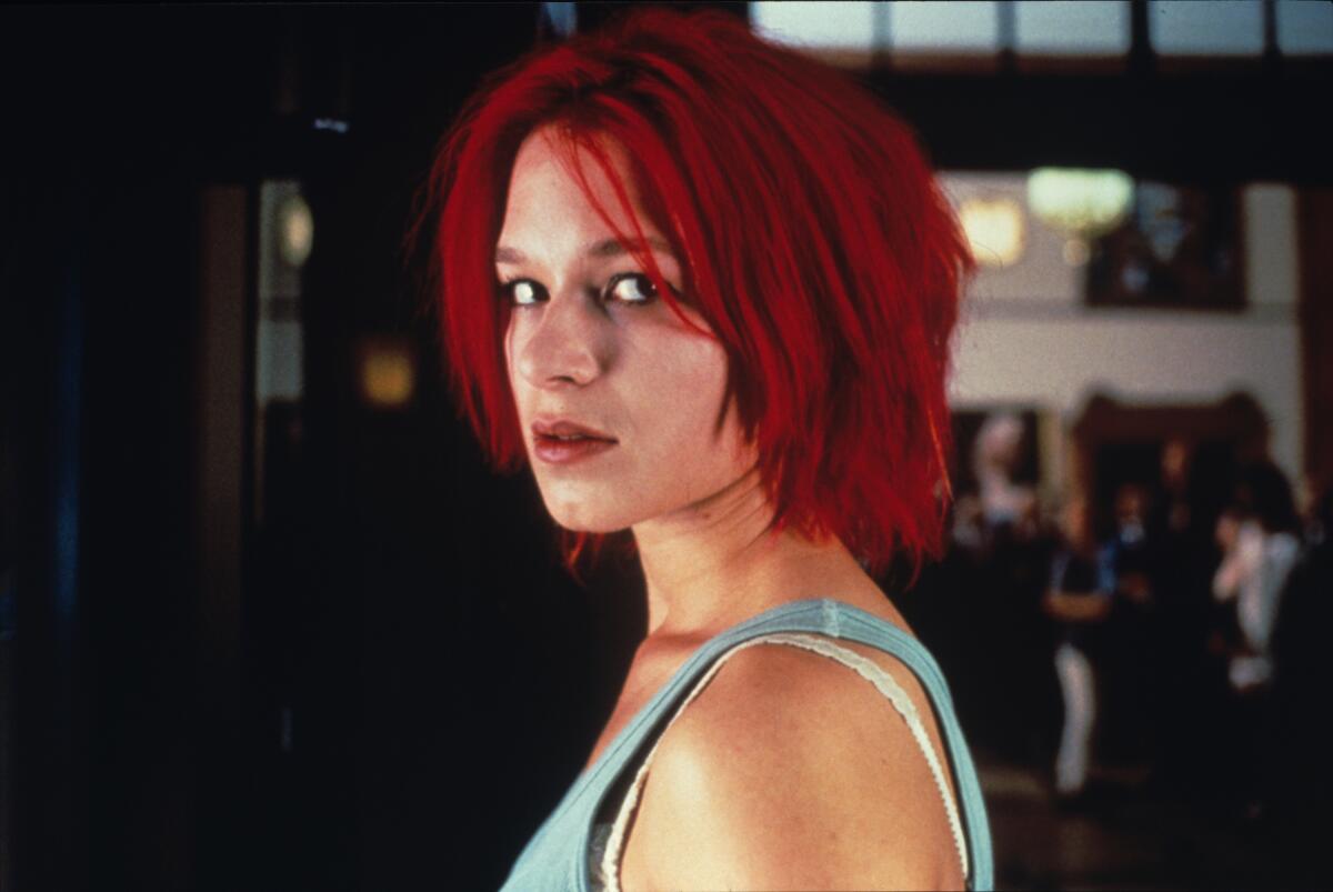 A woman with red hair stares down the lens.