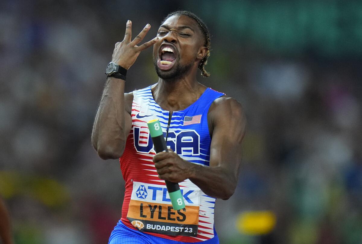 Noah Lyles holds up three fingers as he celebrates anchoring his team to gold in the 4x100 relay.