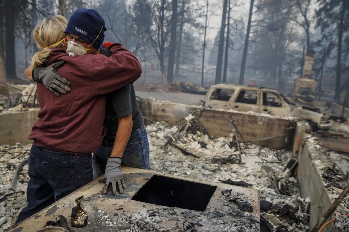 Michael John Ramirez hugs his wife, Charlie Ramirez, as they sift through the remains of their Paradise, Calif., home