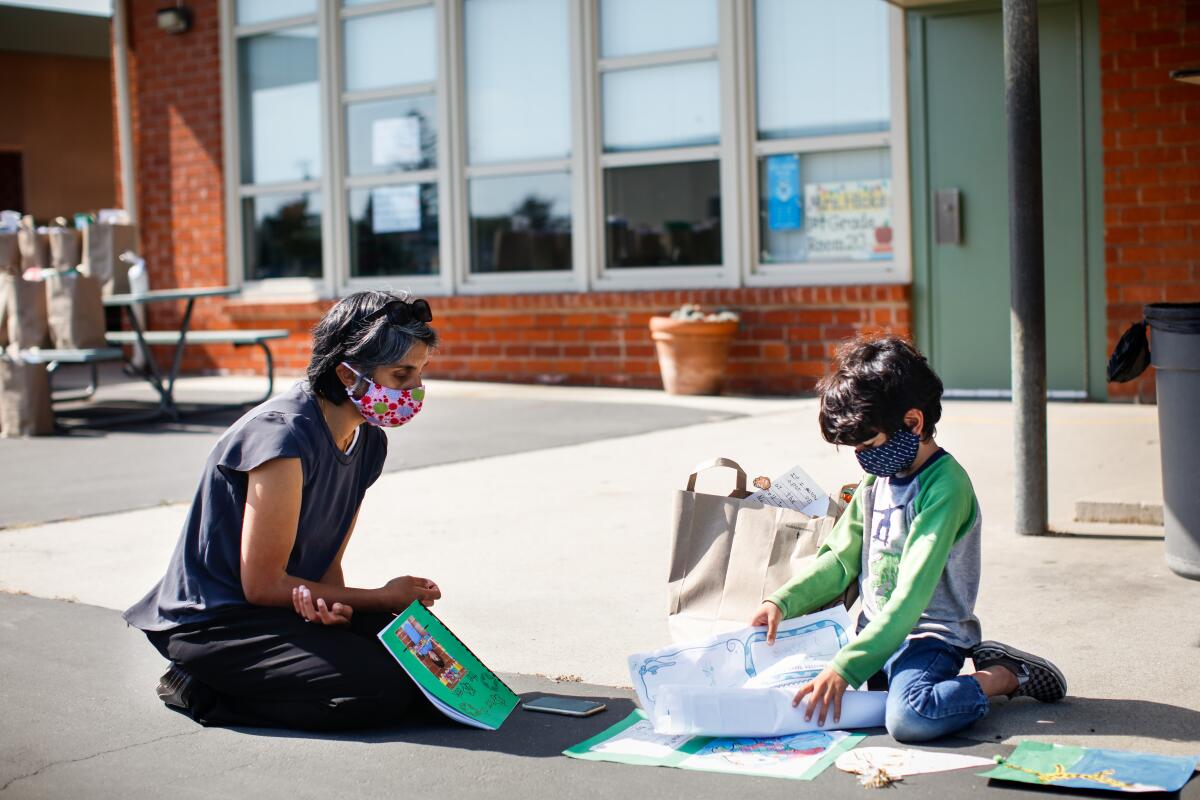 A child shows his mother his schoolwork at Center Street School in El Segundo in June.