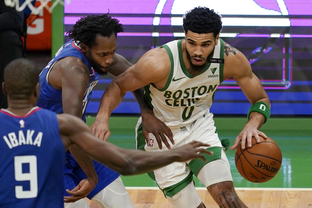 Boston Celtics forward Jayson Tatum drives against Clippers guard Patrick Beverley and center Serge Ibaka.
