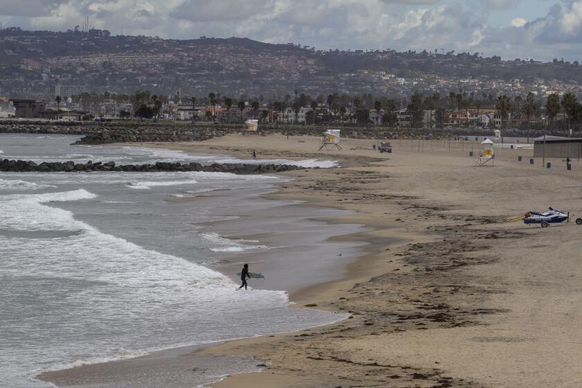 A lone surfer left the beach at Ocean Beach on Tuesday morning, March 24, 2020. San Diego Police and lifeguards were warning surfers to get out of the water because the beaches are closed.