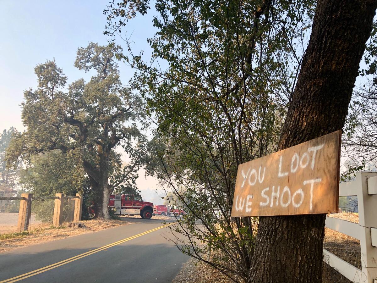 A sign reads "you loot we shoot" in a Sonoma County evacuation zone.