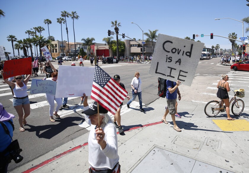 Protesters stand along Mission Blvd. in Pacific Beach during A Day of Liberty rally on Sunday, April 26, 2020. The protesters were against the government shutdown due to the coronavirus.