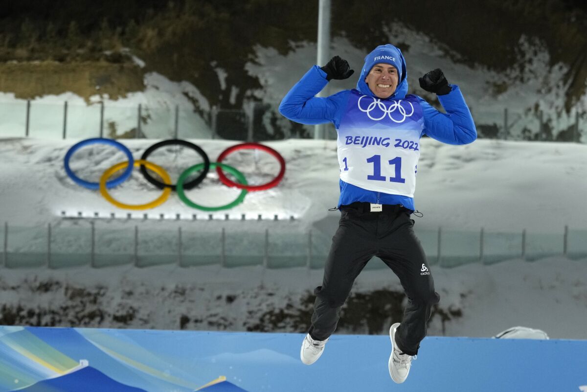 Quentin Fillon Maillet of France leaps on the podium after winning the men's 20-kilometer individual race at the 2022 Winter Olympics, Tuesday, Feb. 8, 2022, in Zhangjiakou, China. (AP Photo/Kirsty Wigglesworth)