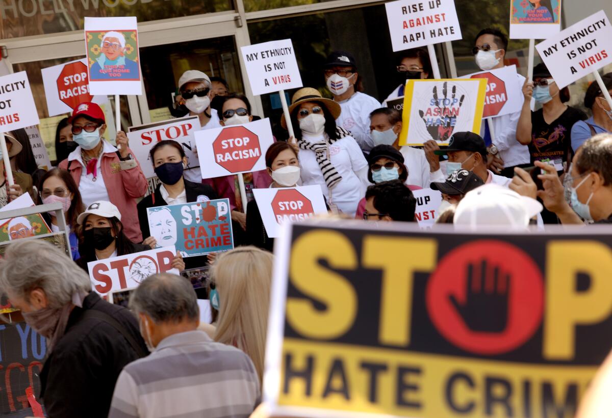 People hold signs that oppose racism and hate crimes at an L.A. rally in April