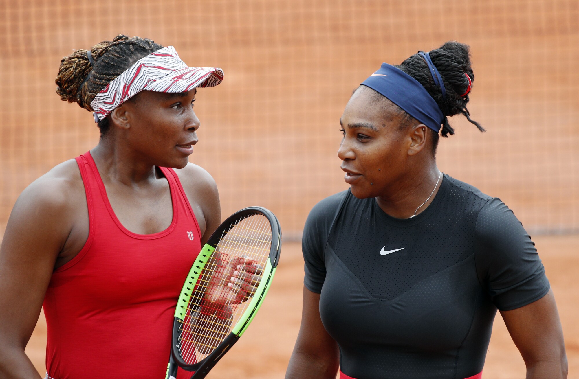 Venus, left, and Serena Williams talk during a doubles match at the French Open in 2018.