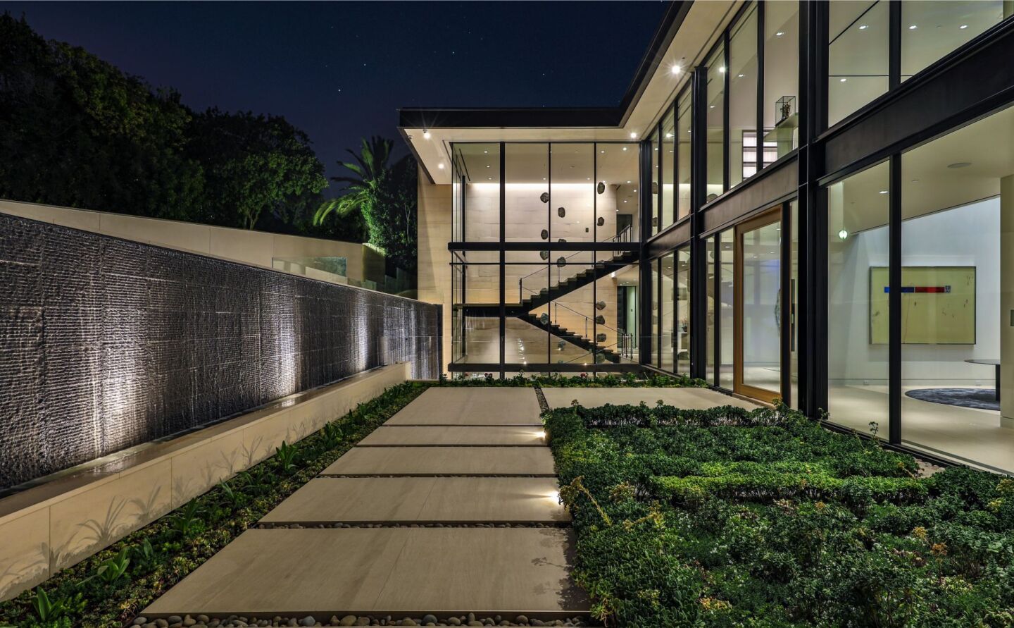 The entry walkway leading to a glass-walled home.