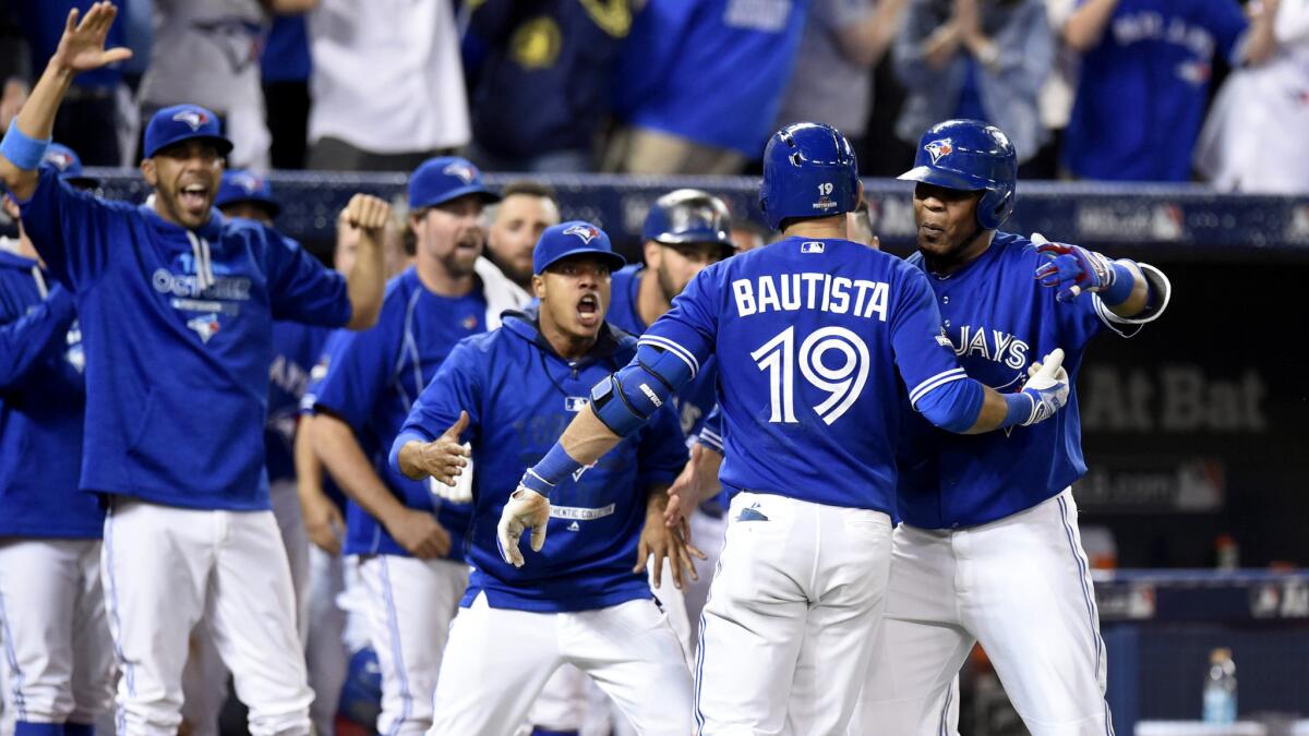 Blue Jays right fielder Jose Bautista is congratulated by teammates as he returns to the dugout after hitting a three-run home run against the Rangers in the seventh inning of Game 5 on Wednesday.