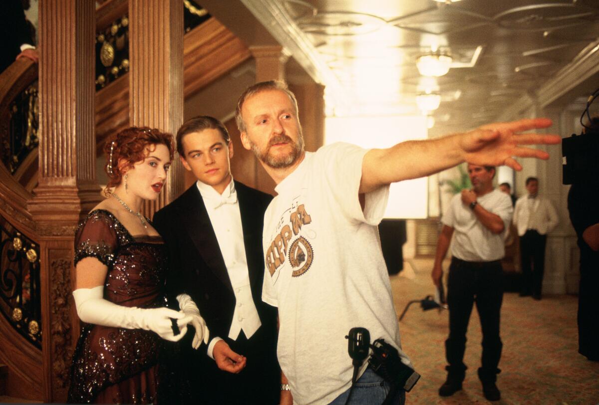A movie director points while two actors are dressed in formal clothing.