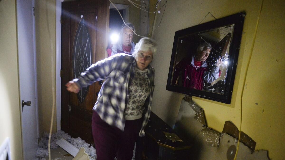 Theresa Wagoner and brother Michael Shell walk into his home after a violent storm moved through Ardmore, Ala., on March 19.