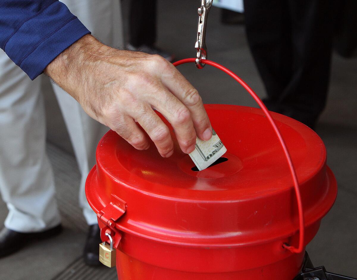 A shopper drops a donation into a Salvation Army kettle in front of Pavilions in Burbank on Monday, Nov. 21, 2016.