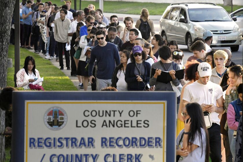 FILE - In this Nov. 6, 2018 file photo potential voters wait in long lines to register and vote at the Los Angeles County Registrar's office in Los Angeles.A pair of propositions on California's November ballot would expand voting rights in California - restoring the vote for parolees and allowing 17-year-olds to vote in primaries if they turn 18 before the general election. (AP Photo/Mark J. Terrill, File)