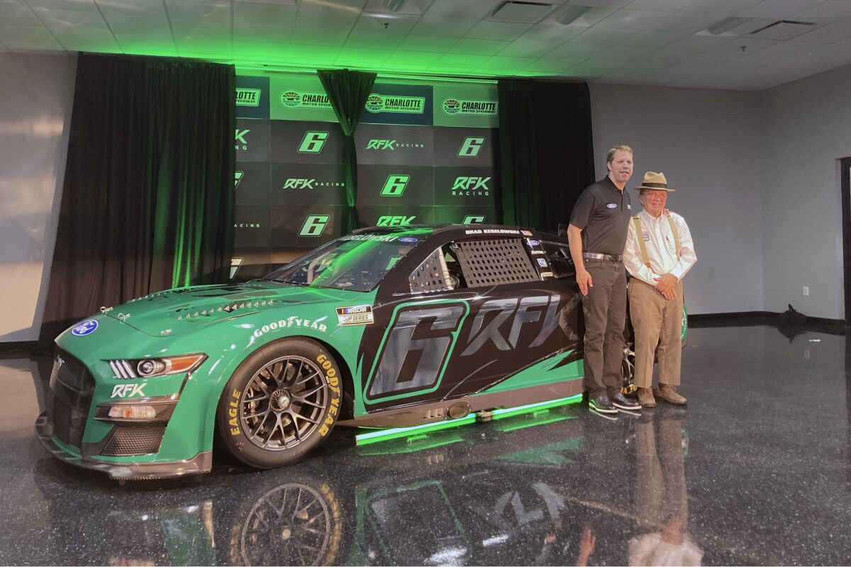 Brad Keselowski, left, stands next to Jack Roush in front of the No. 6 Ford that displays the new team name Roush Fenway Keselowski Racing, which will be called RFK Racing, on Tuesday, Nov. 16, 2021, at Charlotte Motor Speedway in Concord, N.C. (AP Photo/Jenna Fryer)