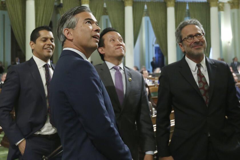 Assemblyman Rob Bonta, D-Alameda, second from left, begins to smile as the votes needed to pass a bail reform bill he co-authored with Sen. Bob Hertzberg, D-Van Nuys, are posted in the California Assembly, Monday, Aug. 20, 2018, in Sacramento, Calif. The bill was sent to the Senate for a final vote. (AP Photo/Rich Pedroncelli)