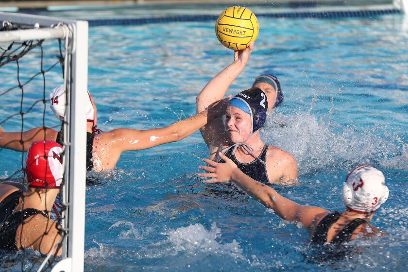 Newport Harbor's Harper Price (2) tries to get a shot off as Sophie Colliday (14) defends in front of the goal during girls' water polo Surf League opener on Tuesday.