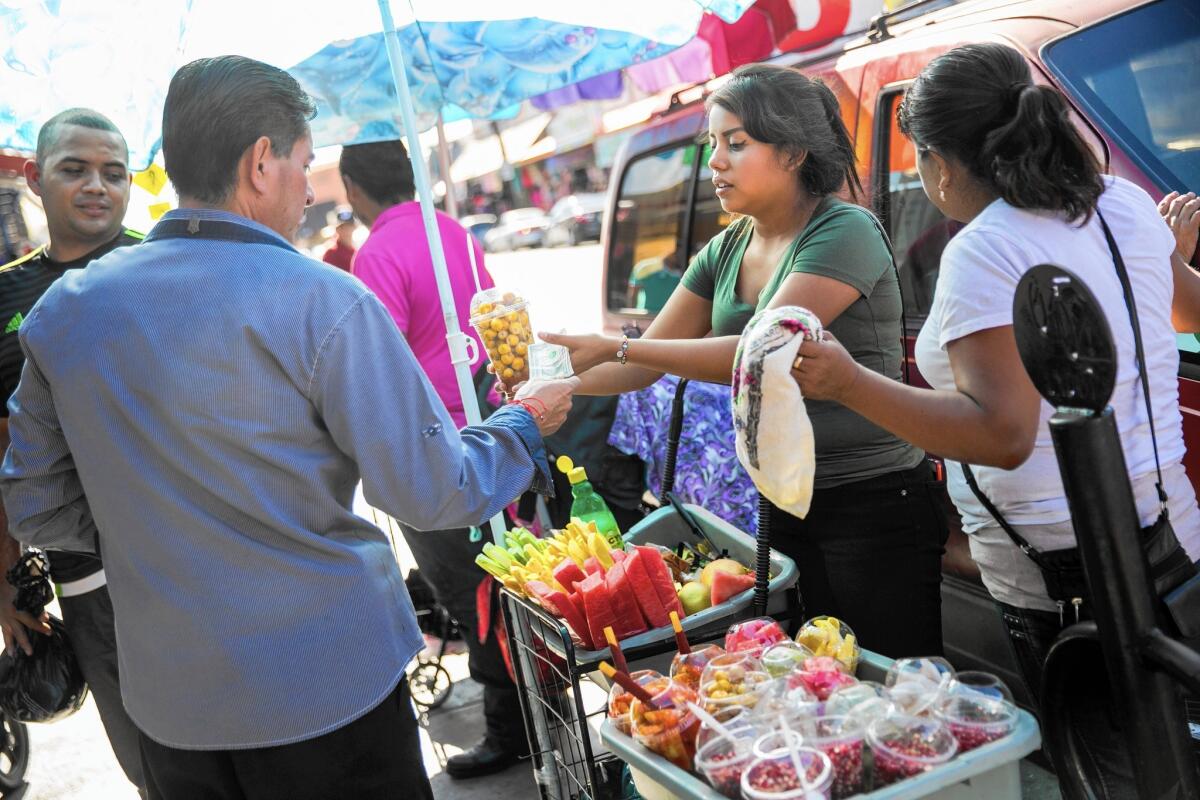 Glodavina Lopez, center right, sell fruits and helps her mother Lili Lopez, right, a street vendor for the past 17 years, in the Fashion District in Los Angeles.