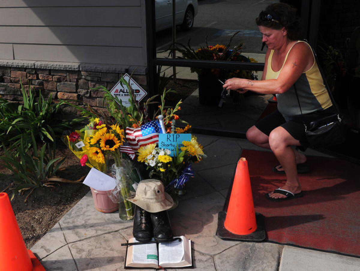 Lill Duncan takes a photo of a memorial for Delbert Belton, an 88-year-old World War II veteran who was beaten to death, in Spokane, Wash. Police arrested a second suspect on Monday.