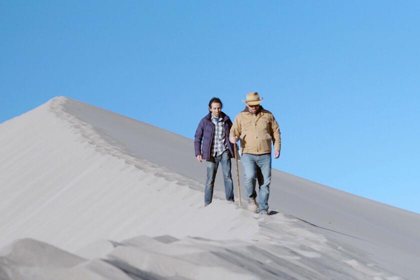 Sammy Roth and biologist Patrick Donnelly walk on a ridge in Big Dune, Nev.
